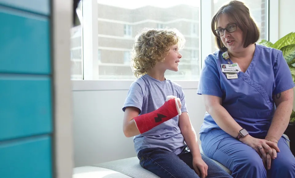 Nurse talking to young patient with a cast on wrist