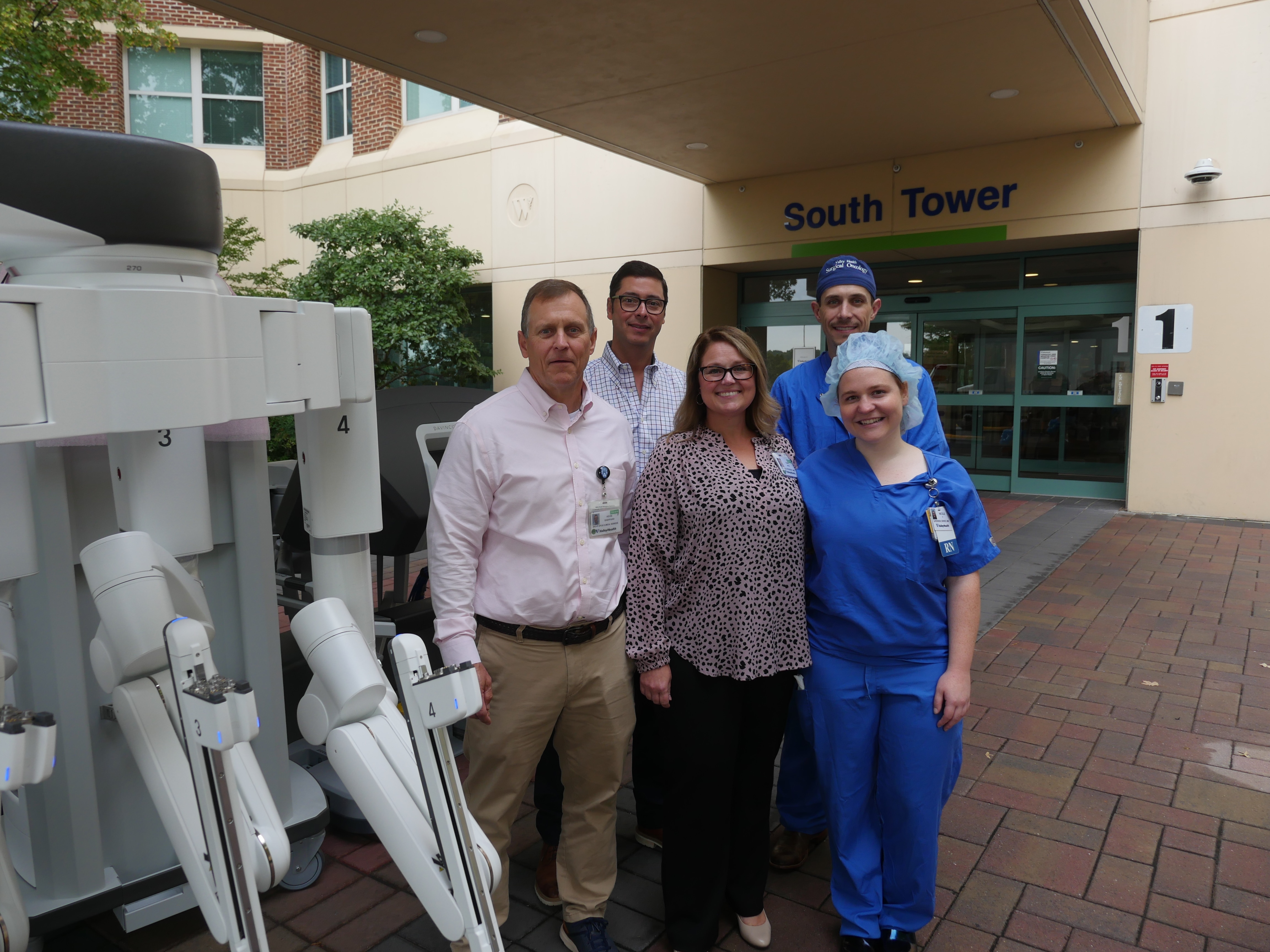 Group of people next to robobtics surgical equipment