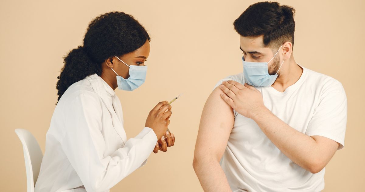 woman giving vaccine to man;