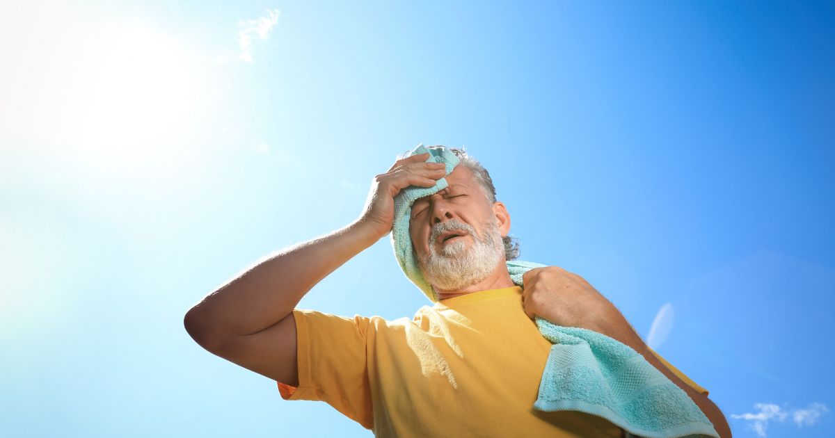 man in sun wiping face with towel