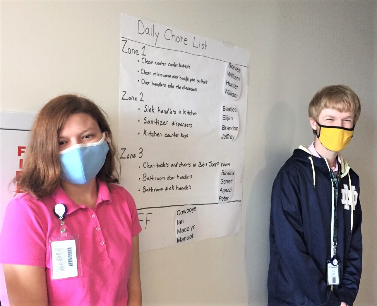 Madelyn Walters and Elijah Stine in masks standing on a wall