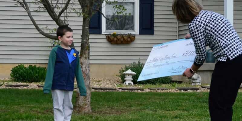 Lady giving a huge check to a kid