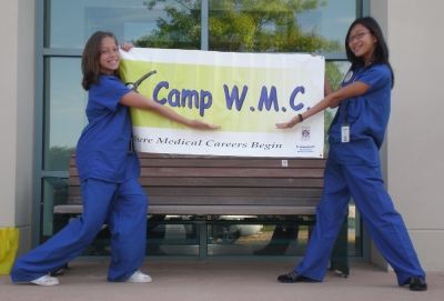 2 younger girls holding a CAMP WMC sign